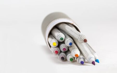 Colored pencils getting out from a gray box on a white surface.の写真素材