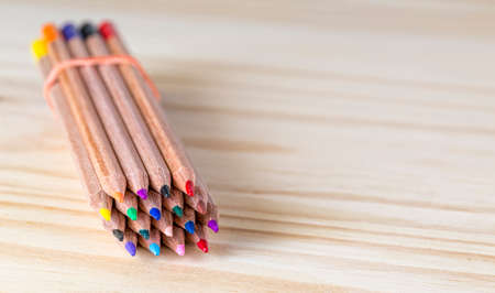 Image of a bundle of colored pencils on a wooden table.の写真素材
