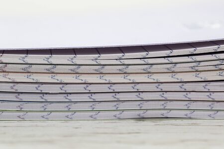 Close-up image of a stack of colorful notebooks on a white wooden table.の写真素材