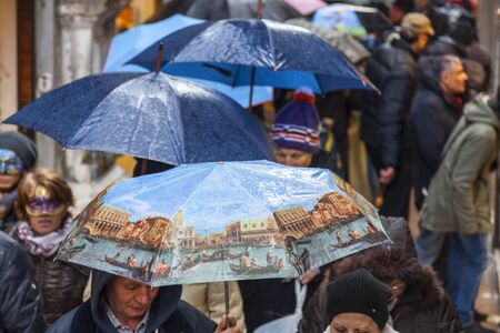 Venice,Italy- March 2, 2014: Crowd of people with umbrellas walking in the rain in a narrow Venetian street during the Venice Carnival days.のeditorial素材