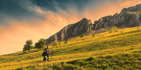 Young man with nordic sticks hiking at dusk in Apuseni Mountains in Transylvania,Romania.の写真素材