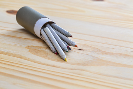 Colored pencils getting out from a gray box on a white surface.の写真素材