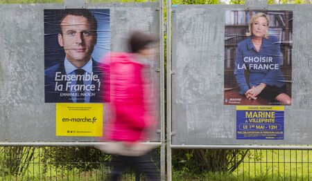 FRANCE,MAY 03,2017: A blurred woman walking past electoral posters displaying the remaining two French presidential candidates Emmanuel Macron and Marine Le Pen which will compete for the second round on May 7, 2017.のeditorial素材
