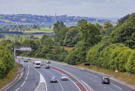 Moderate traffic on a highway between the forests in Normandy,France.