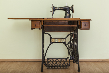 Bacau,Romania - May 16, 2011: Image of the old Singer Sewing machine in a empty room with parquet. Issac Singer built the first sewing machine with vertical needle movement powered by foot treadle.のeditorial素材