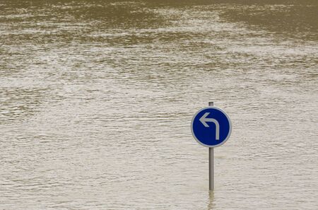 Image of a pole with a traffic sign almost covered by the water of a river that rose during flood. Image on the River Seine in Paris during January 2018.の写真素材