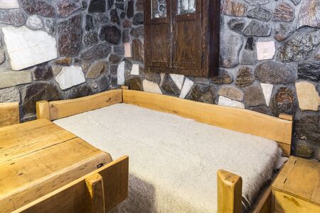 Traditional Romanian wooden bed covered by a whool blanket (cerga) in a hostel chalet in Transylvania.の写真素材