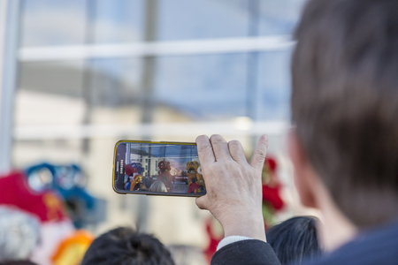 Noisy-le-Grand, France - February 18,2018: Image of a hand of a senior woman filming using a smartphone during the Chinese New Year parade in Nosy-le-Grand on February 18,2018.のeditorial素材