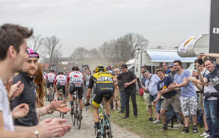 Templeuve, France - April 08, 2018: Rear view of a group of cyclists riding in the peloton on the cobblestone road in Templeuve during Paris-Roubaix 2018.のeditorial素材