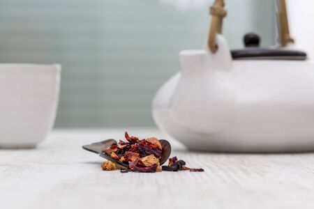 Fruit tea in a wooden spoon is on a table in front of a kettle and a cup in a tea room.の写真素材