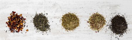 View from above of bunches of various tea types on a white wooden surface.の写真素材