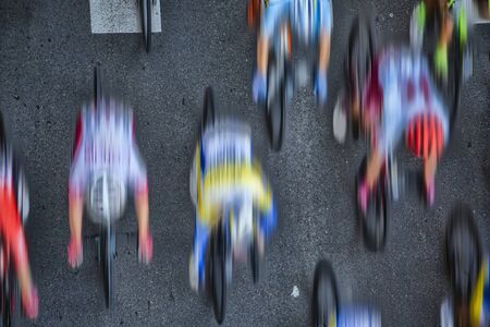 Abstract aerial blurred image of cyclists riding in the pleoton at full speed on an asphalt road.の写真素材