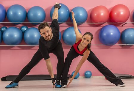 Young couple doing stretching exercises in a gymの写真素材
