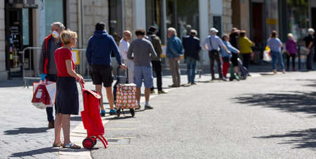 Chartres, France - Avril 18, 2020: People waiting in line respecting the social distance rulles to access an open street market, during the lockdown time due to the coronavirus crisis 2020のeditorial素材
