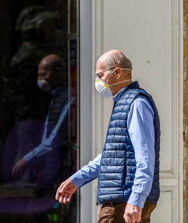 Chartres, France - Avril 18, 2020: Environmental portrait of an unidentified man with a protective mask walking in the street during the lockdown time due to coronavirus crisis in 2020.のeditorial素材