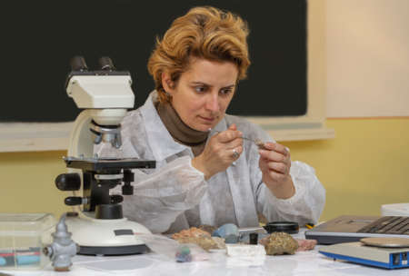 Female geologist researcher analyzing a rock at her workplace.