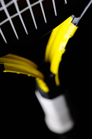 Yellow tennis racket isolated black backgroundの写真素材