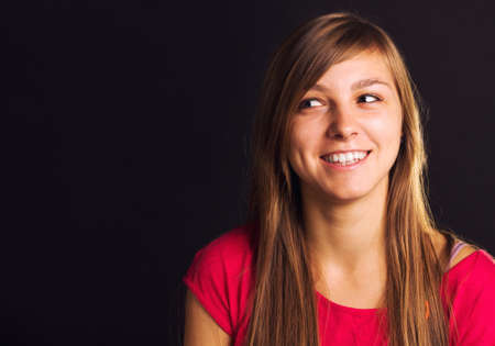 The portrait of a young, blonde girl looking to side, isolated on black.の写真素材