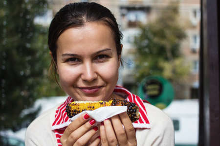 Hungry girl eating baked corn の写真素材