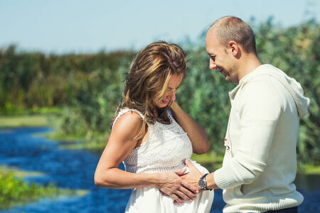 Caring husband while touching his pregnant wife's bellyの写真素材