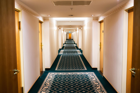 Perspective of a hotel hallway with room doors and warm lightのeditorial素材
