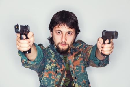 Portrait of a determined young bearded man holding two guns - isolated on whiteの写真素材
