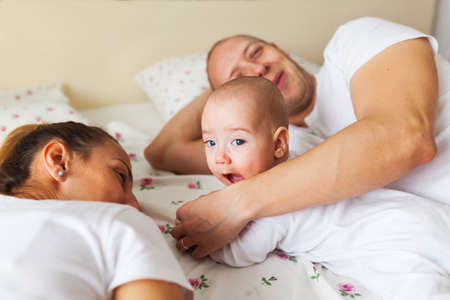 Young parents spending quality time with their baby boy in bed