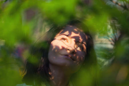 Dreaming young woman between sun beams and shadows