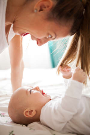Happy baby boy laughing while pulling his mother's hairの写真素材