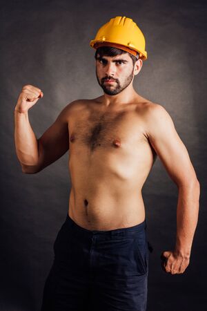 Bearded construction worker with a yellow hard hat - isolated on black.の写真素材