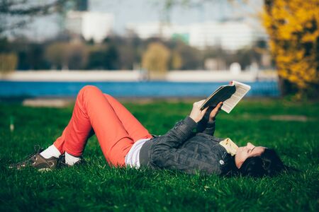 Girl lying on grass, reading and enjoying the momentの写真素材