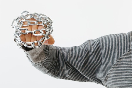 Anonymous male hand holding a metal chain - isolated on whiteの写真素材