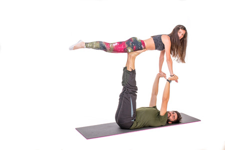 Fit couple performing acro yoga pose on a mat-isolated on whiteの写真素材