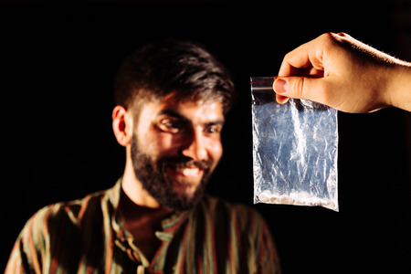 Drug dealer giving to an addict a packet of heroin or cocaineの写真素材