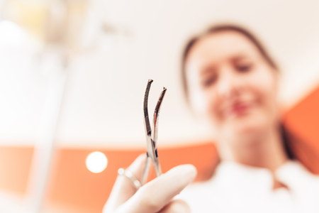 Woman dentist holding a dental instrument, her face is blurred