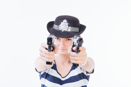 Young woman with police hat is holding two guns in her hands - isolated on whiteの写真素材