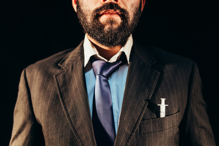 Drug addict in nice suit having a syringe in his pocket