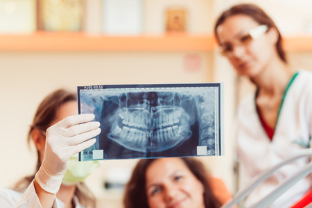 Dentist and female patient looking to x-ray