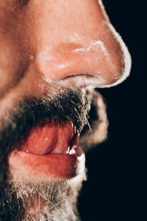 Man feeling good after sniffing cocaine and licking cocain of his mustache.の写真素材