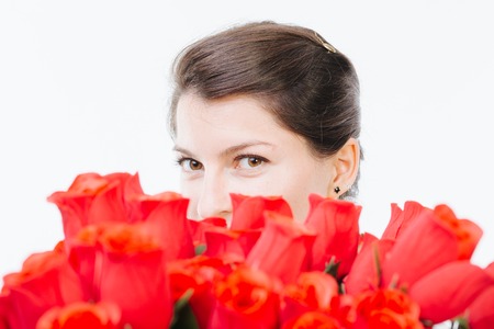 Mysterious woman hiding behind red roses - isolated on whiteの写真素材