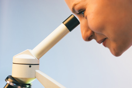 Profile portrait of a woman looking through a microscope in labの写真素材