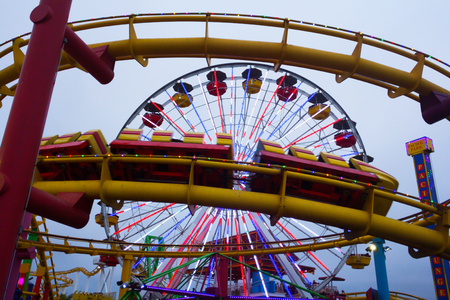 Los Angeles, CA, USA - July 6, 2013: Moving roller coaster in foreground and Ferris Wheel in...