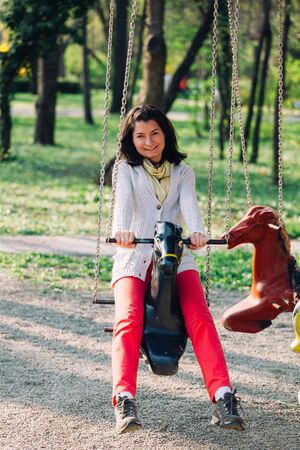 Happy woman plays in modern children toy playground in park.の写真素材