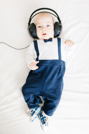 Elegant baby boy wearing headphones and lying in bedの写真素材