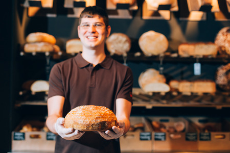 Closeup of a salesman holding tasty fresh bread