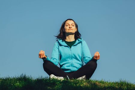 Young relaxed woman doing yoga exercise in the parkの写真素材