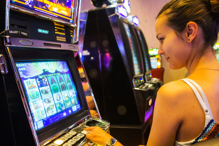 LAS VEGAS - JULY 13, 2013: Woman playing slot machines in The Quad Resort and Casino.のeditorial素材