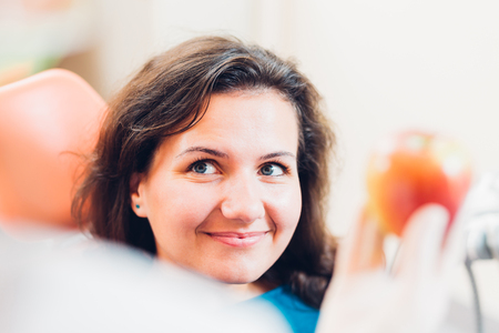 Doctor's hand holding an apple and smiling patient looking at the doctor. Focus on the patient.の写真素材