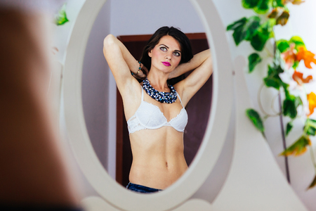 Fashion attractive woman standing in front of the mirror and arranging herself.の写真素材