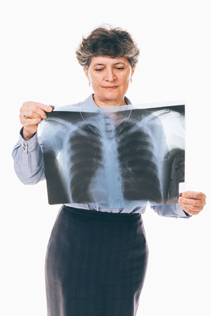 Confused senior woman is examining lungs radiography holding it in front of her chest - isolated on...